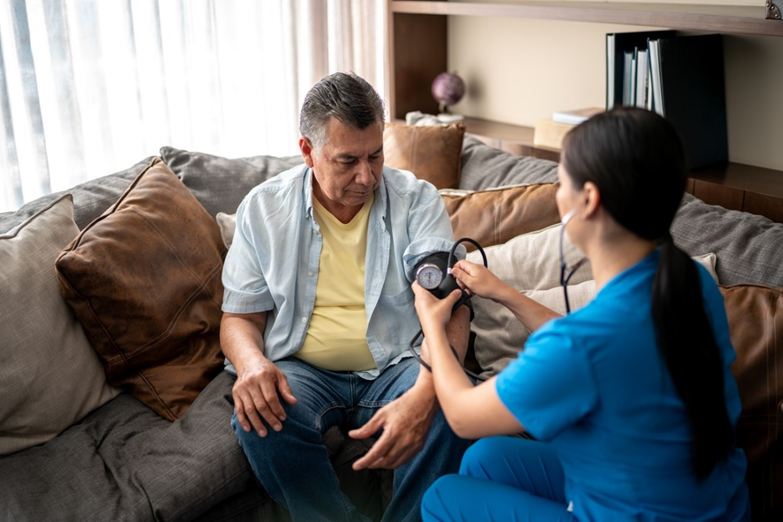 Female home health nurse measuring senior man's blood pressure